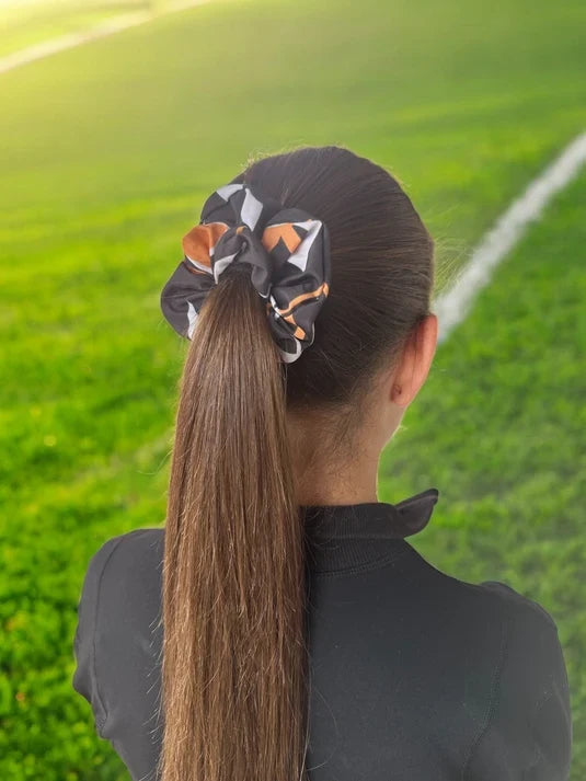 Girl wearing sport orange and black patterns hair scrunchies on sport field