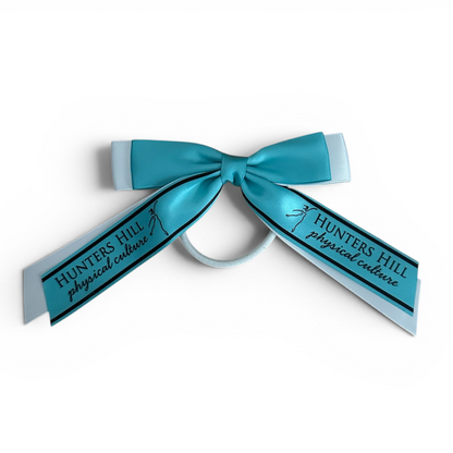 A teal and white ribbon hair bow with the text 'HUNTERS HILL physical culture' printed on the ribbon tails, shown on a plain white background.