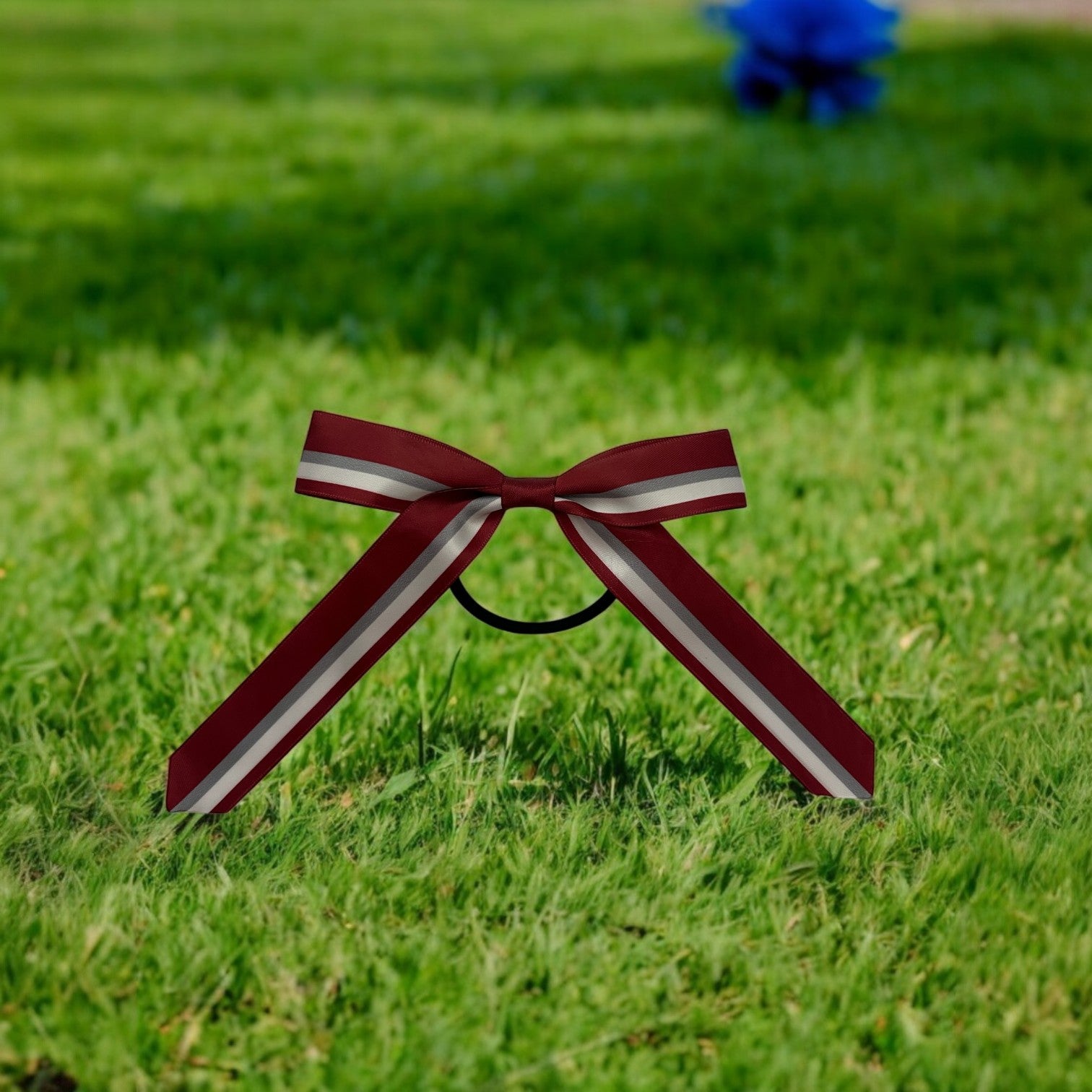 Maroon and white striped bow on grass