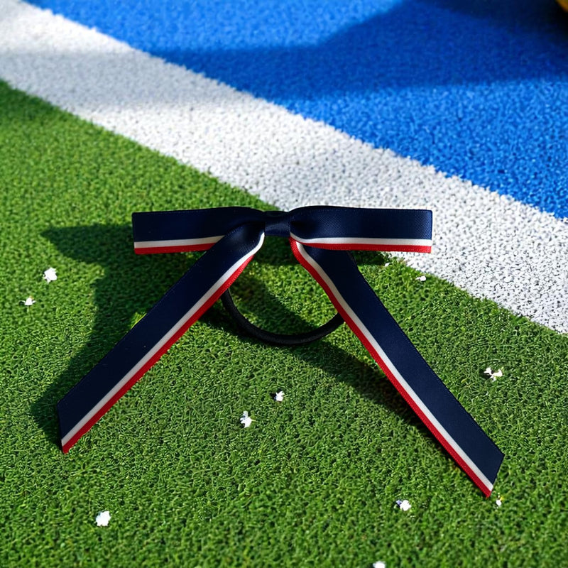 Navy blue hair bow with red and white stripes on a grassy field