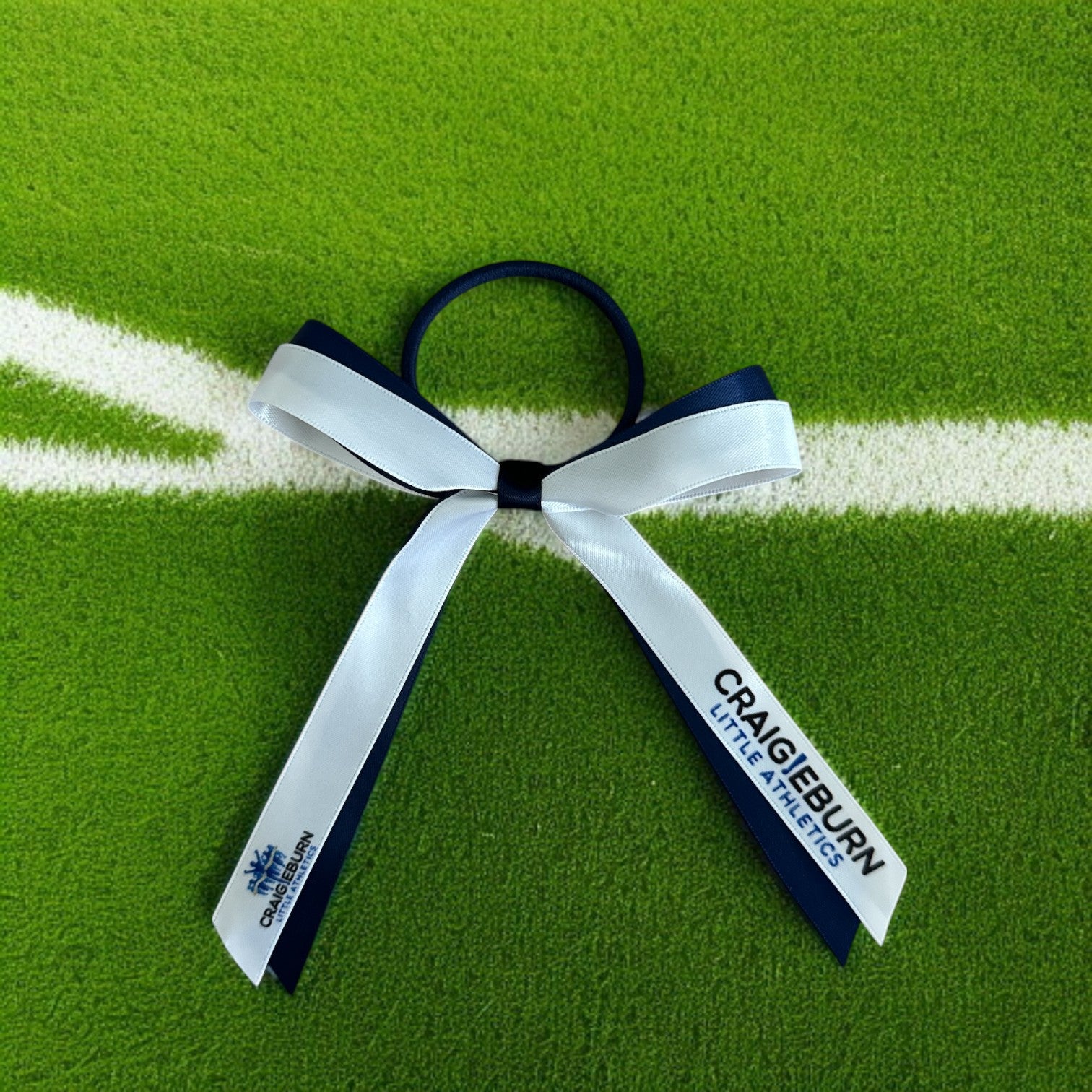 White bow with black hair tie on a green field